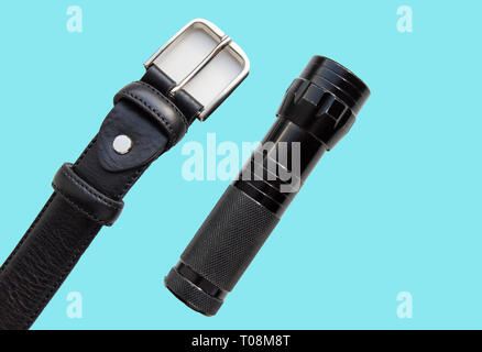 Accessoires pour hommes bracelet en cuir noir et lampe isolé sur fond bleu. Banque D'Images