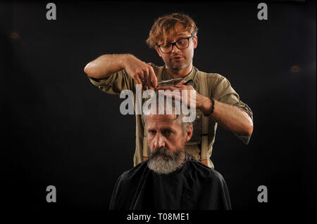 Coiffure Coupe Senior citizen avec une barbe sur fond sombre dans le studio Banque D'Images