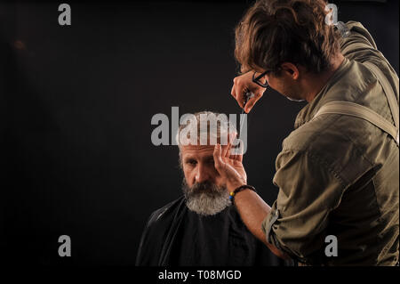 Coiffure Coupe Senior citizen avec une barbe sur fond sombre dans le studio Banque D'Images