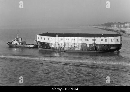 AJAXNETPHOTO. 1971. PORTSMOUTH, Angleterre. - Départ de l'ANCIEN COMBATTANT - LA CARCASSE D'EX HMS Gannet (EX Gannett, T.S.EX MERCURE) REMORQUÉ HORS DE LA BASE NAVALE APRÈS UNE COURTE REPOSER. PHOTO:JONATHAN EASTLAND/AJAX REF:711912 Banque D'Images