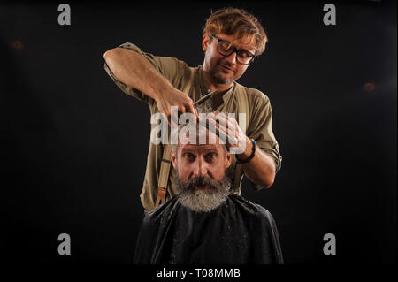 Coiffure Coupe Senior citizen avec une barbe sur fond sombre dans le studio Banque D'Images