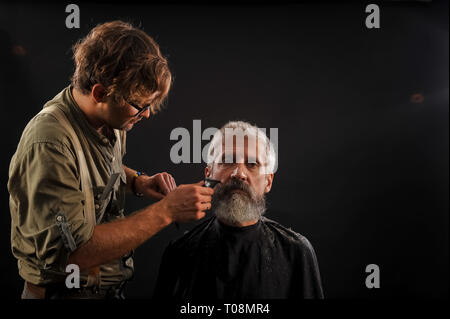 Coiffure Coupe une barbe pour un client d'un homme aux cheveux gris âgés dans le studio Banque D'Images