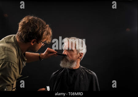 Coiffure Coupe une barbe pour un client d'un homme aux cheveux gris âgés dans le studio Banque D'Images