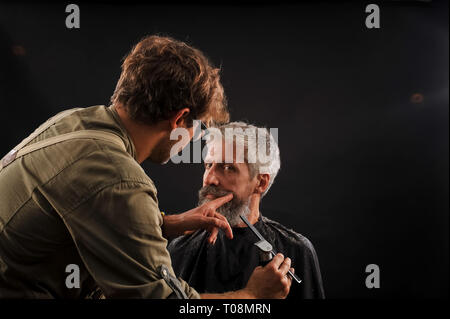 Coiffure Coupe une barbe pour un client d'un homme aux cheveux gris âgés dans le studio Banque D'Images