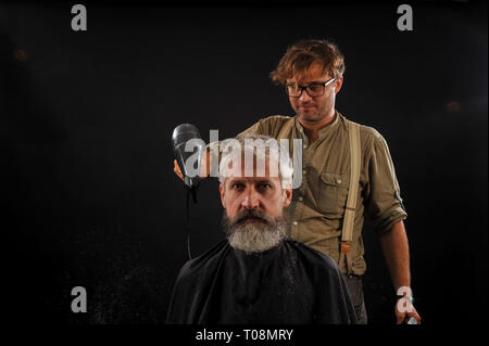 Coiffure Coupe une barbe pour un client d'un homme aux cheveux gris âgés Banque D'Images