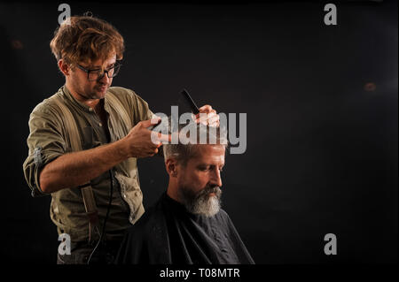 Coiffure Coupe Senior citizen avec une barbe sur fond sombre dans le studio Banque D'Images