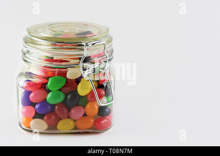 Un assortiment de bonbons dans un bocal en verre avec couvercle. Isolé sur fond blanc. Copie de l'espace sur le côté droit. Banque D'Images