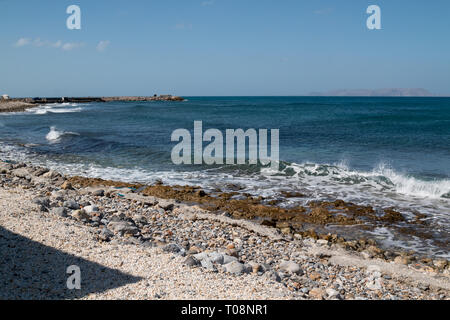 Côte avec des pierres et rochers. Turqouise couleur de la mer Méditerranée avec de petites vagues écumeuses. Horizon de la mer. Ciel bleu. Gouves, Crète, Grèce. Banque D'Images