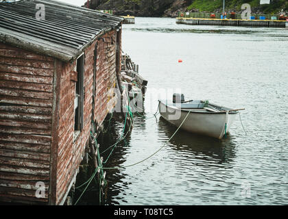 Petit bateau de pêche attaché à un abri de pêche dans un port sûr, le long de la côte de Terre-Neuve, Canada. Banque D'Images