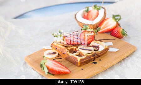 Gaufres Belges aux fruits et sauce au chocolat est magnifiquement servi sur une planche de bois. À côté des fraises et noix de coco Banque D'Images