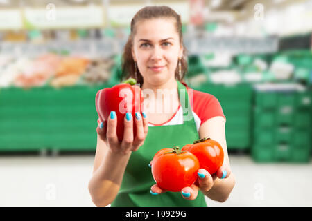 Épicerie hypermarché femelle ou employé qui présente deux tomates rouge gros plan sur la main Banque D'Images