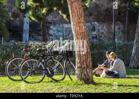 Un couple, des gens se relaxant sous les arbres, des vélos garés à l'arbre de pin, Valencia Turia Gardens, Espagne vélo ville amis dans le parc avec vélo, pelouse Banque D'Images