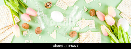 Pessah célébration concept. Pâque juive avec l'arrière-plan de matzo, oeufs, fleurs de printemps, vin, fond vert copie espace bannière Vue de dessus Banque D'Images