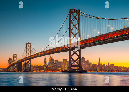 Classic vue panoramique de San Francisco skyline avec célèbre Oakland Bay Bridge illuminée en magnifique lumière du soir au coucher du soleil en été Banque D'Images