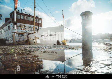 Belle vue de vieux bateau dans le port de Stockholm qui reflète de flaque dans la pittoresque ville de lumière du soir au coucher du soleil, de la Suède, Scandinavie Banque D'Images