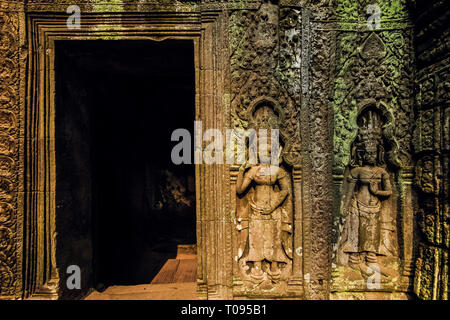 Bas-relief par divinités devata permanent porte dans l'UNESCO 12thC temple Khmer Ta Prohm complexes. Angkor, Siem Reap, Cambodge. Banque D'Images