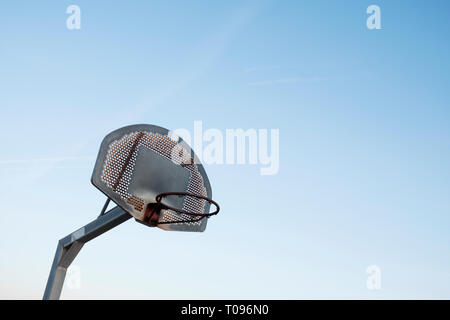 Libre d'un panier de basket-ball extérieur rouillé, sans le net, contre le ciel bleu au-dessus, avec un espace vide sur la droite Banque D'Images