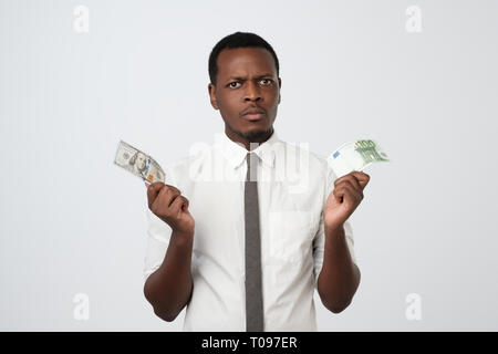 Young attractive african man holding USA devise et monnaie euro de décider lequel choisir. Banque D'Images