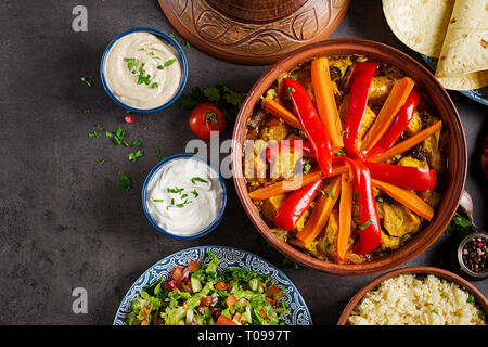 La cuisine marocaine. Tajine, couscous plats traditionnels et salade fraîche sur table en bois rustique. Tajine de poulet et légumes. Une cuisine arabe. Haut Banque D'Images