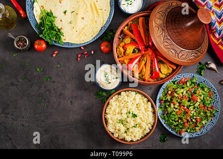 La cuisine marocaine. Tajine, couscous plats traditionnels et salade fraîche sur table en bois rustique. Tajine de poulet et légumes. Une cuisine arabe. Haut Banque D'Images