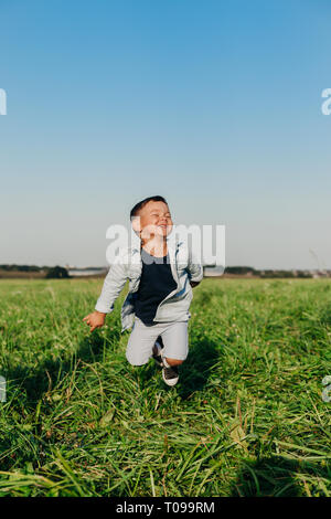 Heureux petit garçon sautant sur l'herbe en été journée ensoleillée
