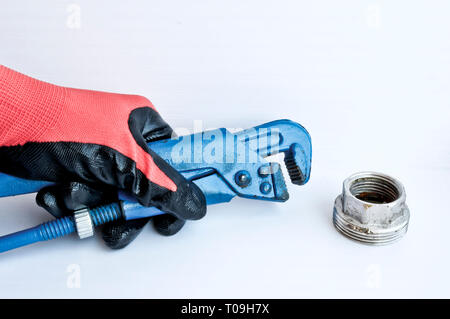 Clé à molette de gaz dans la main d'un homme dans un gant de travail rouge. Outil de serrurier. Banque D'Images