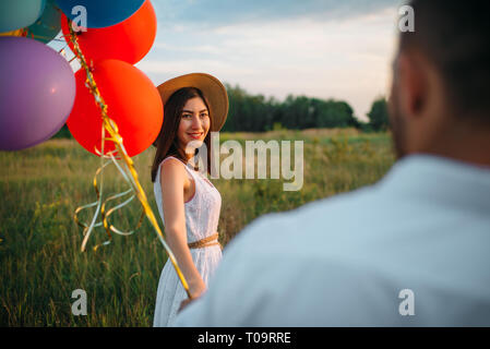 Heureux femme bouquet de ballons, deux en été. Joli couple loisirs sur pré vert Banque D'Images