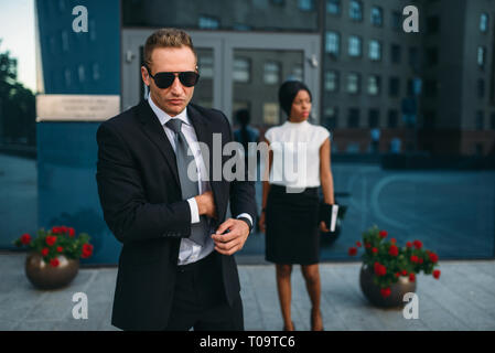 Garde du corps en costume et lunettes de soleil, les clients VIP sur l'arrière-plan. Agent de sécurité est une profession à risque, des personnes d'Affaires, Garde prote Banque D'Images