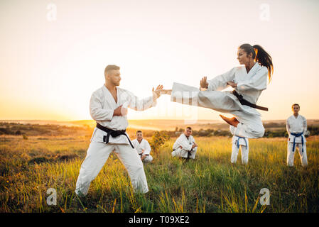 Les trains de combat karaté féminin en vol avec un coup de maître. Les combattants d'arts martiaux sur l'extérieur d'entraînement, de la technique de la pratique. Photo manipulation avec backgrou Banque D'Images