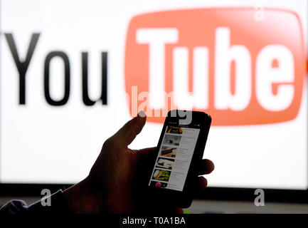 15 mars 2019, le Schleswig-Holstein, Aukrug-Homfeld : ILLUSTRATION - Un smartphone est tenue devant le logo de la plate-forme Internet YouTube. Photo : Carsten Rehder/dpa Banque D'Images