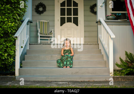 Portrait d'une jeune fille assise sur le perron d'une maison de banlieue. Banque D'Images