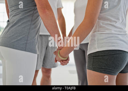 Groupe de personnes debout en cercle et tenir la main pendant un cours de yoga. Banque D'Images