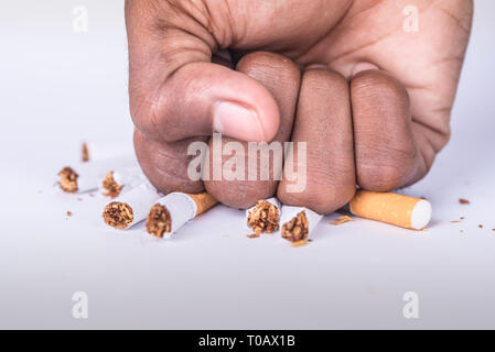 Un concept de fumer à l'arrêt avec une cigarette pilée à la main sur une table blanche à la main Banque D'Images