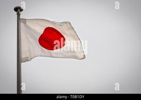 Un drapeau japonais dans le vent sur un jour nuageux. Banque D'Images