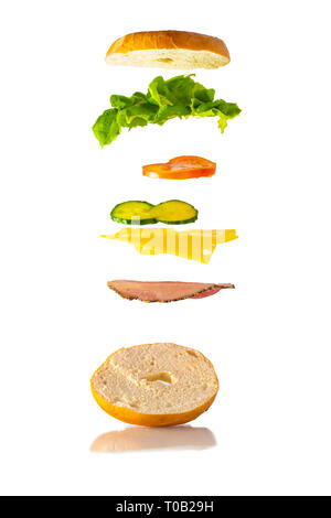 Sandwich Bagel Lévitation flottant relevant des ingrédients. Produits frais et délicieux sandwich magique. Blanc rustique / mur de brique rouge. Chips / croustilles Banque D'Images