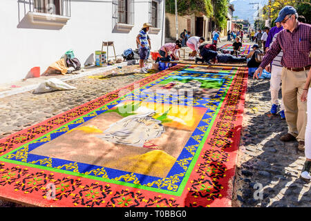 Antigua, Guatemala - Mars 11, 2018 : Les gens d'admirer la sciure teints procession carême dans la ville avec des tapis célèbre célébrations de la Semaine Sainte. Banque D'Images