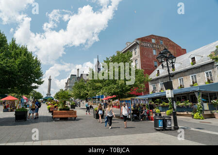 Montréal, Québec, Canada. Les personnes, les bâtiments, et affiche à la Place Jacques Cartier dans le Vieux Montréal, la Colonne Nelson de gauche, en arrière-plan. Banque D'Images