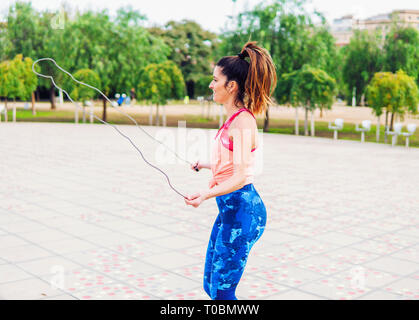 Fit belle femme avec la corde à sauter dans un parc Banque D'Images