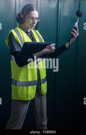 Un arpenteur de l'environnement femmes tests pour le son et le bruit durant une enquête sur un chantier à l'aide d'équipements spécialisés. Banque D'Images