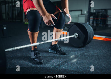 Powerlifter mâle frotte ses mains dans les vêtements de sport avec de la poudre de talc, la préparation à l'exercice avec barbell in gym. Entraînement d'haltérophilie dynamophilie, tr Banque D'Images