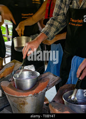 Les touristes à se faire de leçon de cuisine lao asiatique riz gluant violet poêles en argile sur tamarin, école de cuisine, Luang Prabang, Laos Banque D'Images