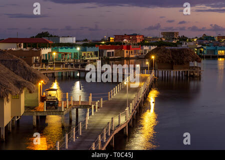 Au-dessus de l'eau et les entrées de cabanas se tenir dehors au milieu des maisons aux couleurs de San Pedro, Ambergris Caye, Belize au coucher du soleil. Banque D'Images