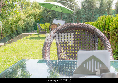 Une chaise avec une table et des tissus sur la table en verre dans un café avec ses plantes vertes luxuriantes Banque D'Images