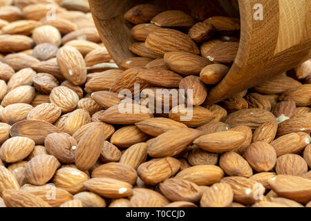 Amandes brutes s'échappant du petit bol en bois Banque D'Images