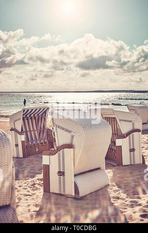 Retro photo stylisée de chaises de plage en osier sur une plage contre le soleil avec des reflets. Banque D'Images