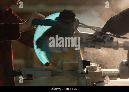 Carpenter couper un morceau de bois avec une scie mécanique à l'atelier Banque D'Images