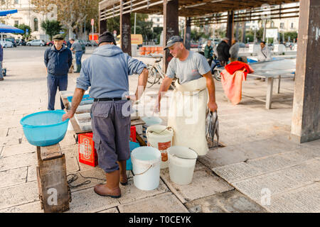 Bari, Pouilles, Italie - 07 novembre 2018 : Fishermans nettoie les poissons fraîchement pêchés, d'être vendus à des clients sur la jetée au centre-ville de Bari, Pouilles Banque D'Images