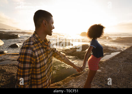 Couple holding hands and standing on rock, près de la mer Banque D'Images