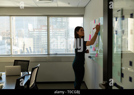 Young female executive écrit sur les notes in a modern office Banque D'Images