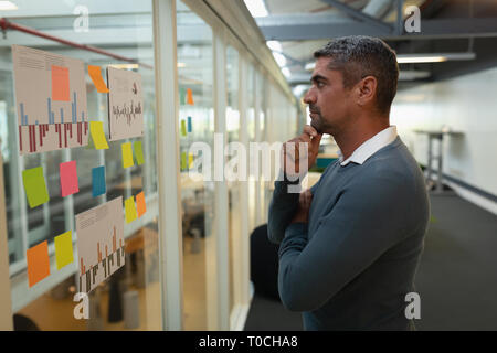 Thoughtful businessman looking over notes in office Banque D'Images